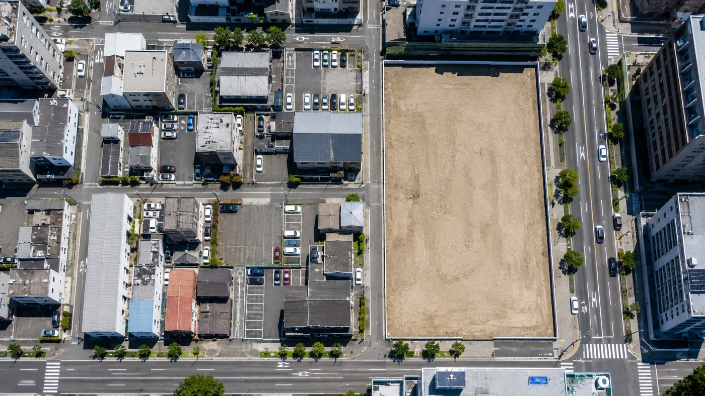 細かく分かれた区画と、整地された一つの大きな区画が対比的に見える街区の航空写真